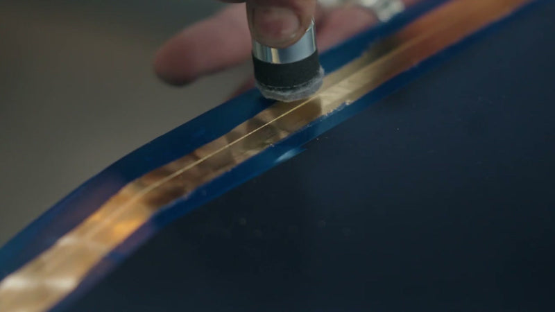 Gold leaf pinstripe being polished on a dark blue custom painted panel