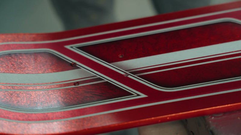 Candy red skateboard deck with silver pinstripes and 3D shadow work
